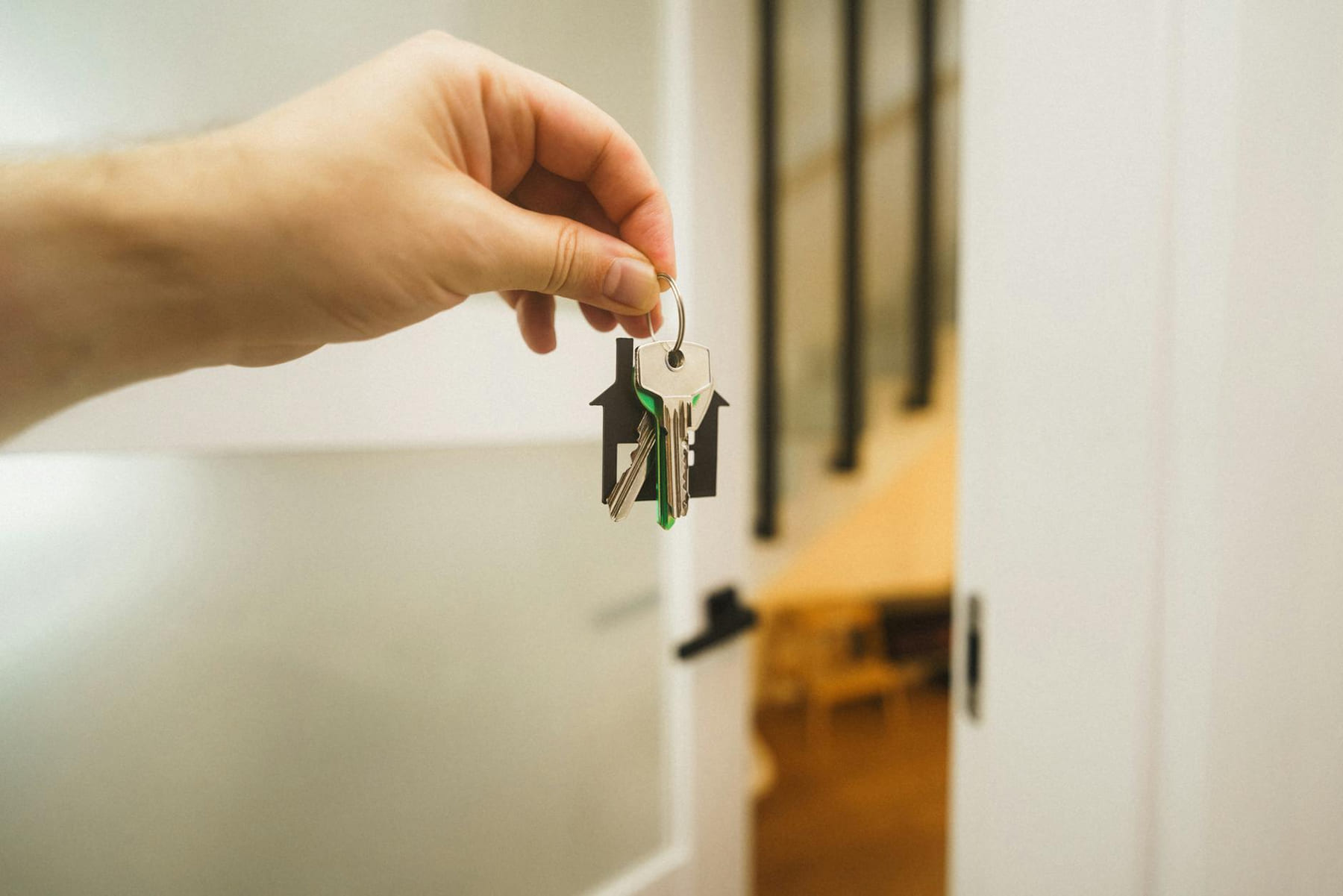 A hand holding a house key indoors signifies new ownership or leasing in real estate. on The Smart Home Buyer