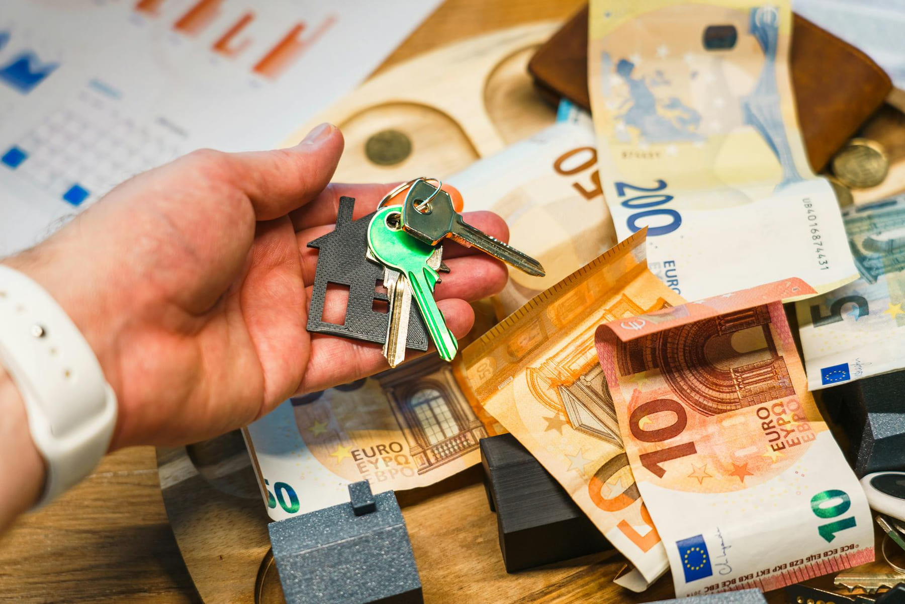 A hand holding house keys over euro banknotes, symbolizing real estate and finance. on The Smart Home Buyer