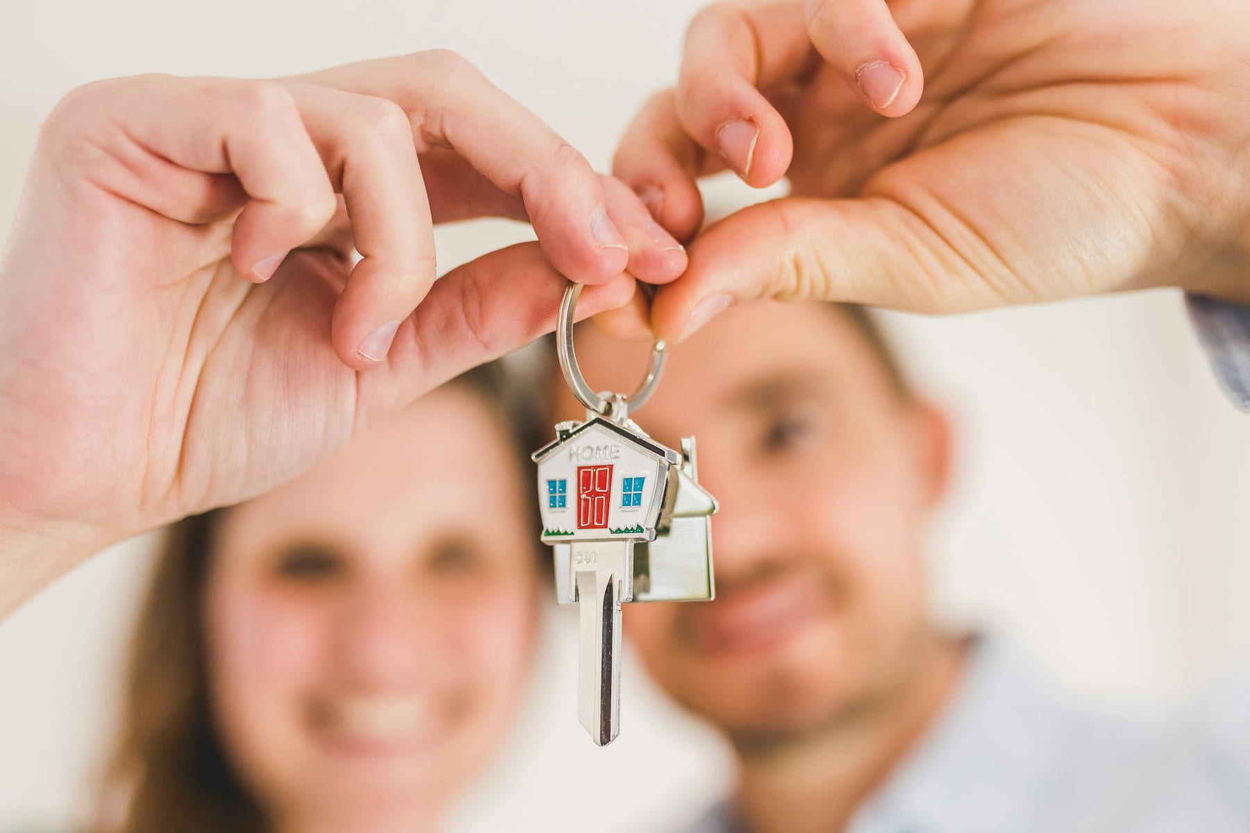 A smiling couple holds a house-shaped key, symbolizing their new home purchase. on The Smart Home Buyer