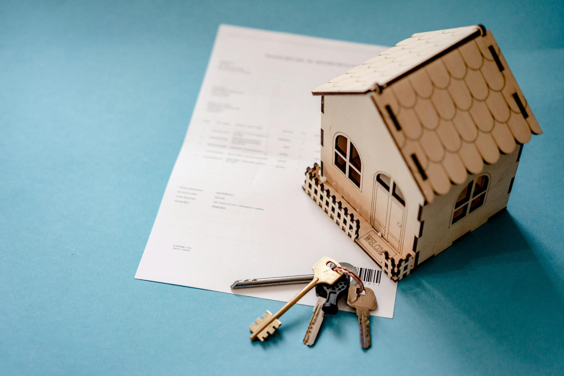 Miniature wooden house with keys and contract symbolizing real estate transactions. on The Smart Home Buyer