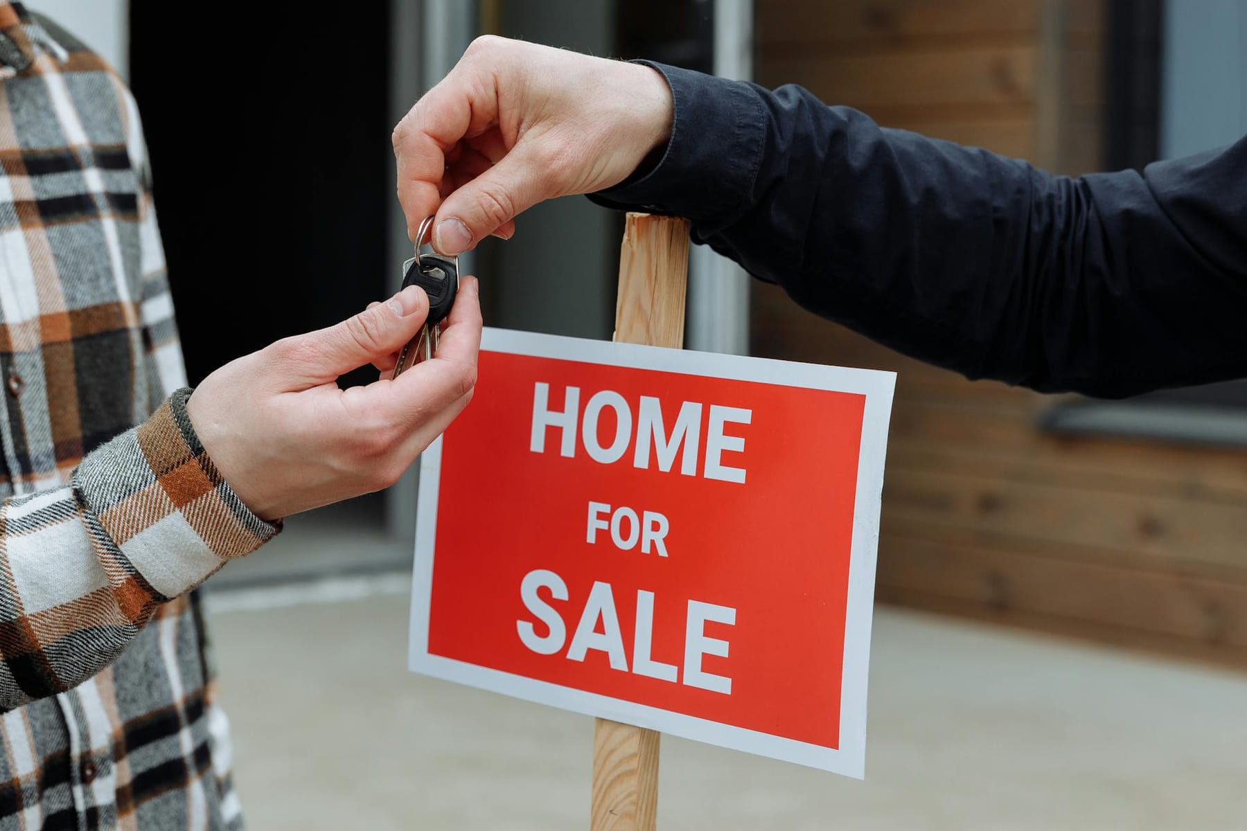 Close-up of a home for sale sign with people exchanging keys. on The Smart Home Buyer