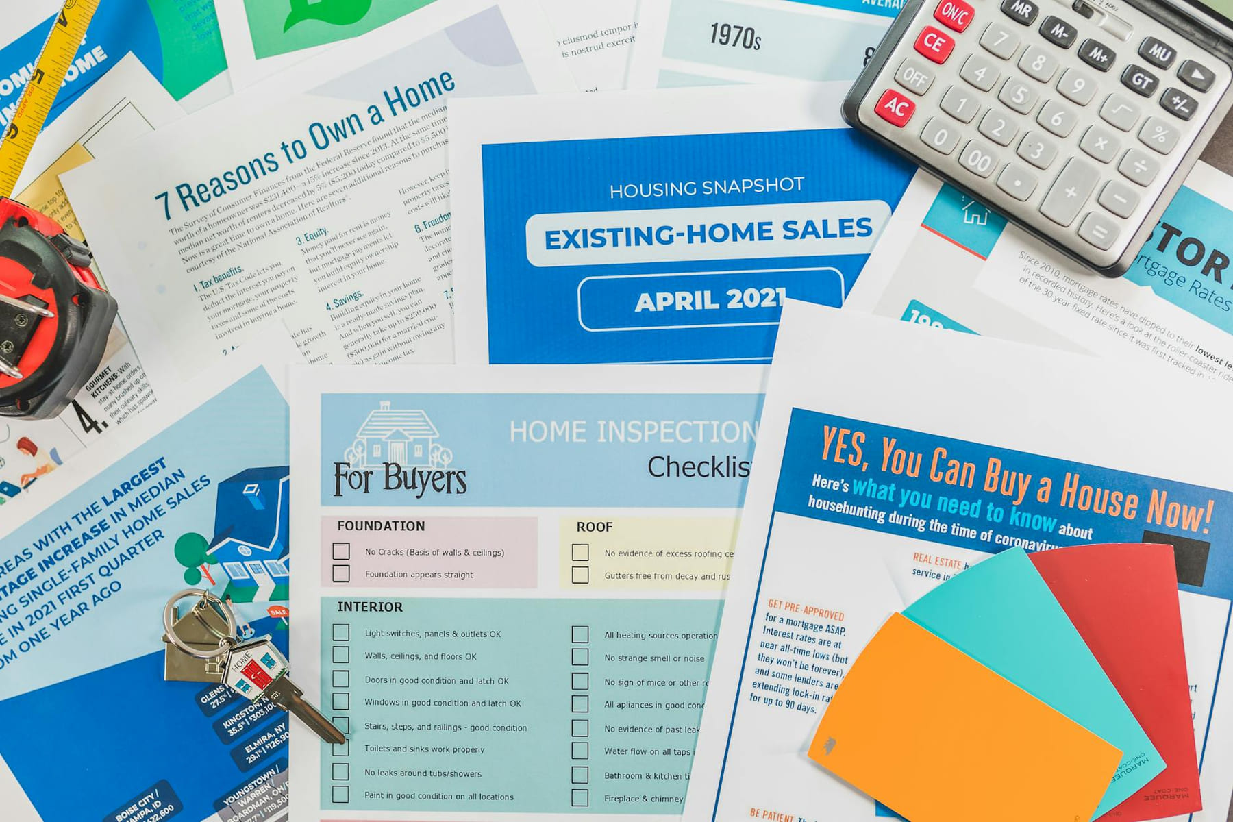 Flat lay of real estate brochures, checklists, and a calculator for home buying. on The Smart Home Buyer