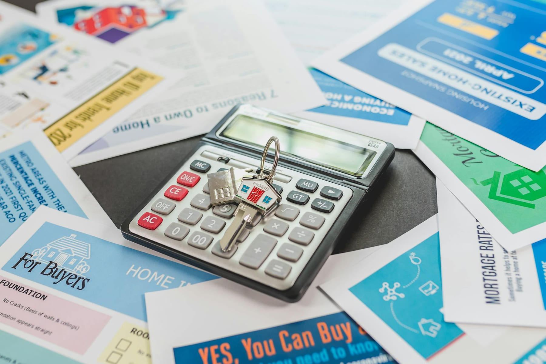 A calculator and real estate flyers depicting financial planning for home buyers. on The Smart Home Buyer