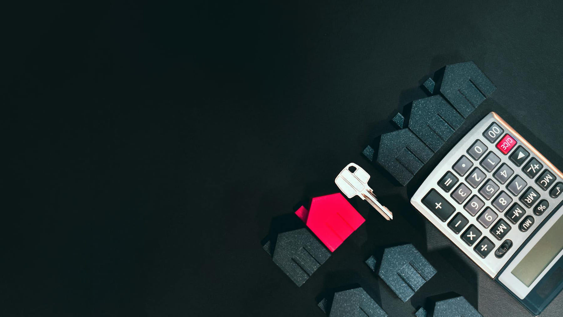 Real estate concept image featuring a calculator, houses, and a key on a black background. on The Smart Home Buyer