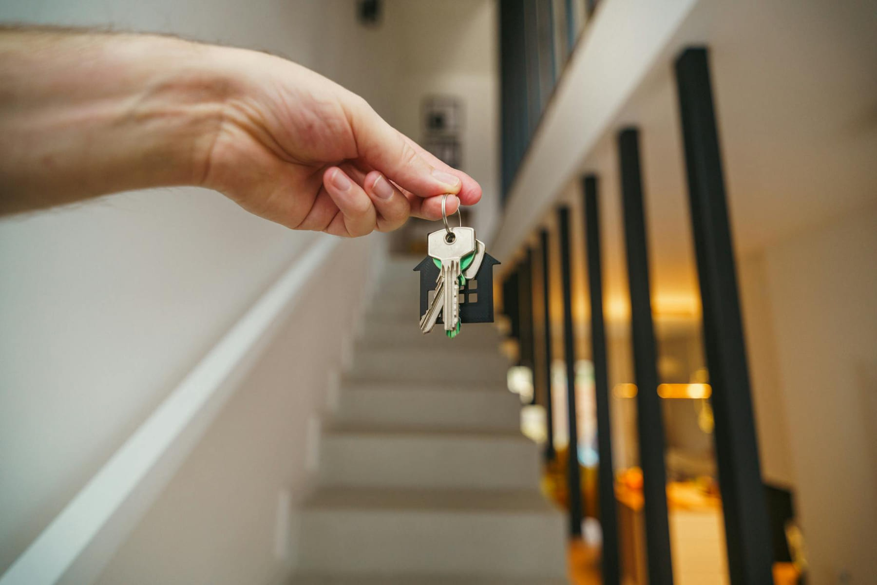 A hand holding house keys in a modern interior, symbolizing new home ownership or real estate investment. on The Smart Home Buyer