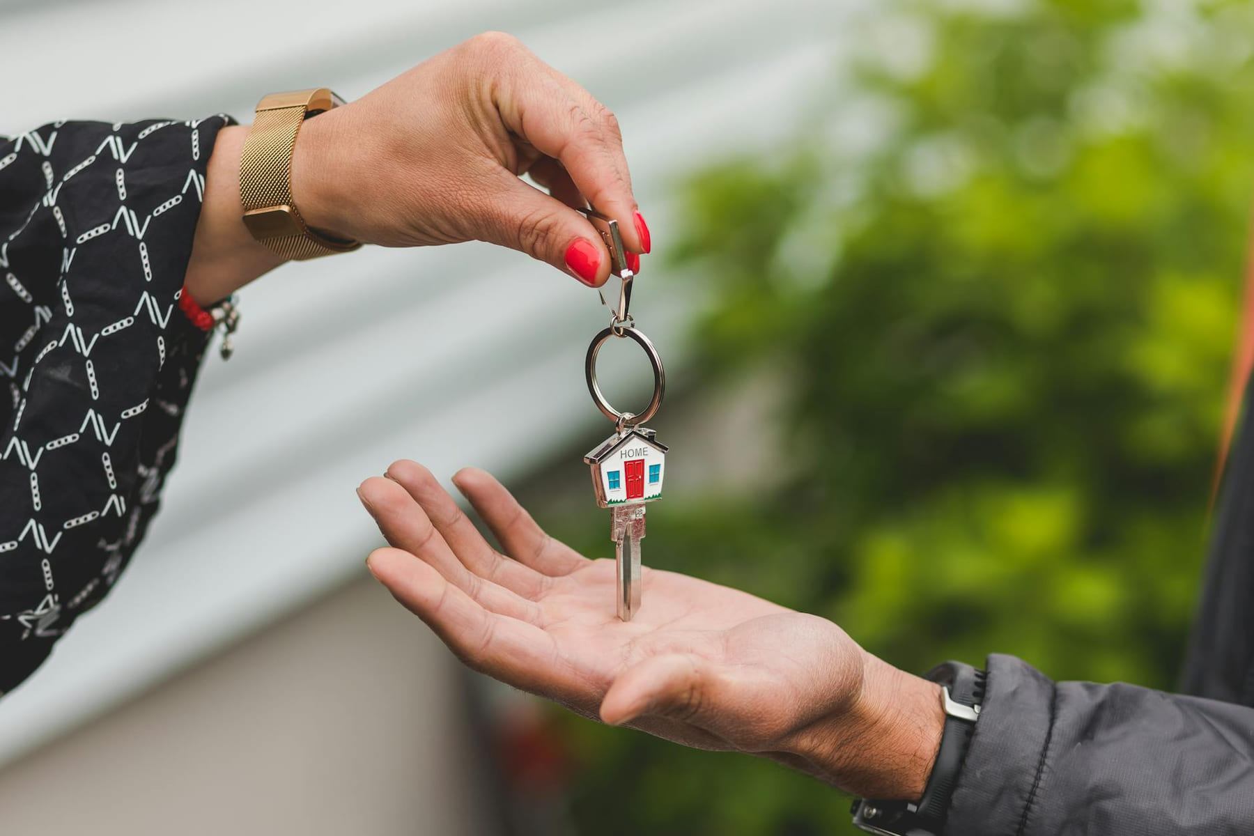 Close-up of a hand handing over a key with a house keychain, symbolizing real estate transaction. on The Smart Home Buyer
