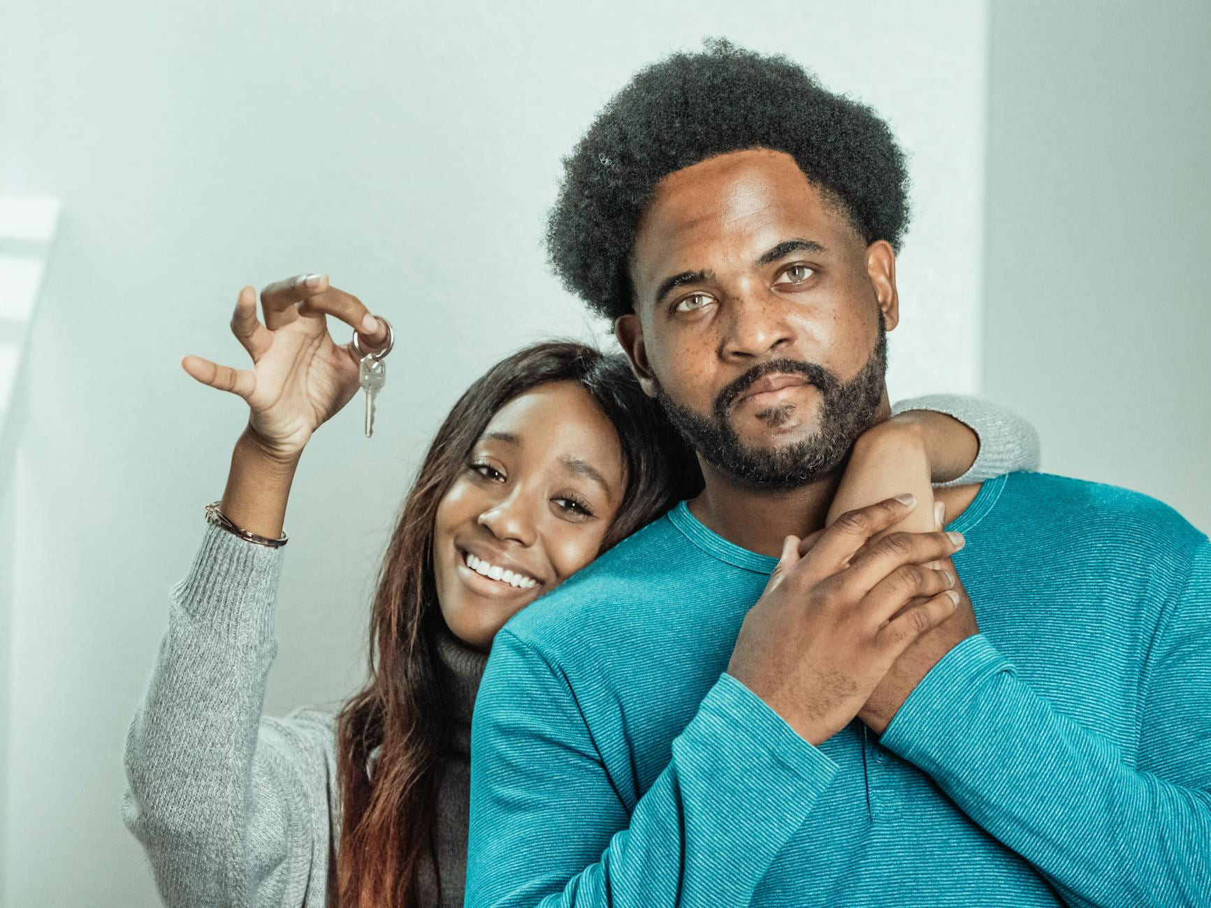 Smiling couple celebrates receiving keys to their new home indoors. on The Smart Home Buyer
