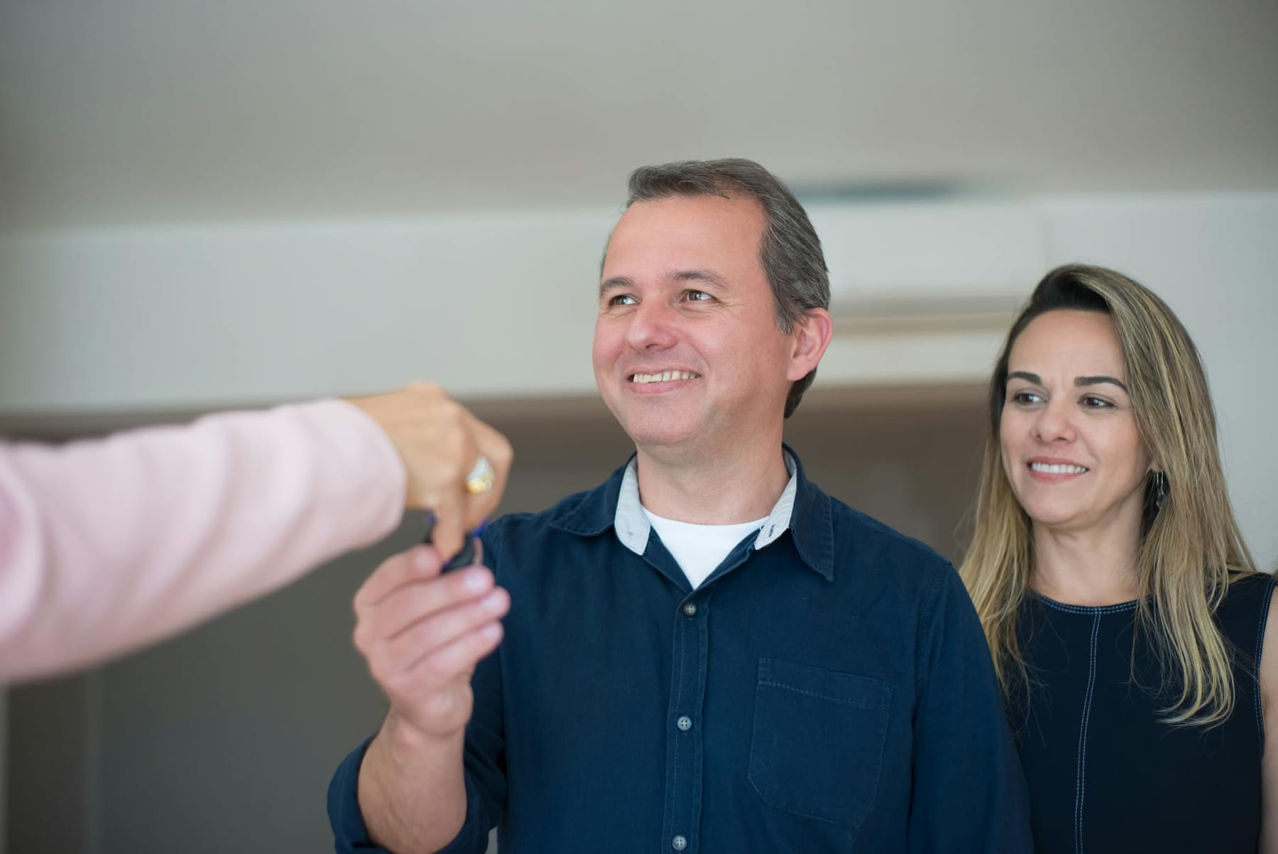 Smiling couple receiving keys, celebrating new home purchase indoors. on The Smart Home Buyer